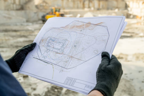 Gloved hands of builder holding paper with sketch of construction